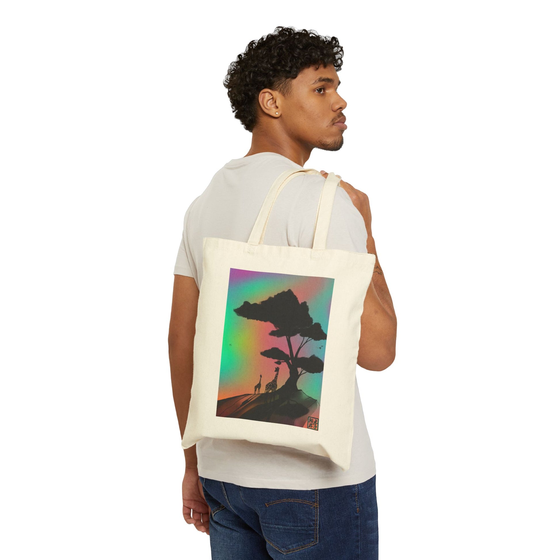 This is the Natural 15" x 16" A Glance Tote Bag design by Lee Hansheng Studios.The handles are color matched.There is an African American gentleman hanging the bag over his shoulder wearing a beige tee and jeans.It is a sillhouette illustration in the middle of the shirt of a large tree rooted in the land.It is an orange red color with shadows reflected on it. One giraffe is in the foreground whereas the other is near the background spotted in black.The background is a mirage of pink, blue, yellow and red.