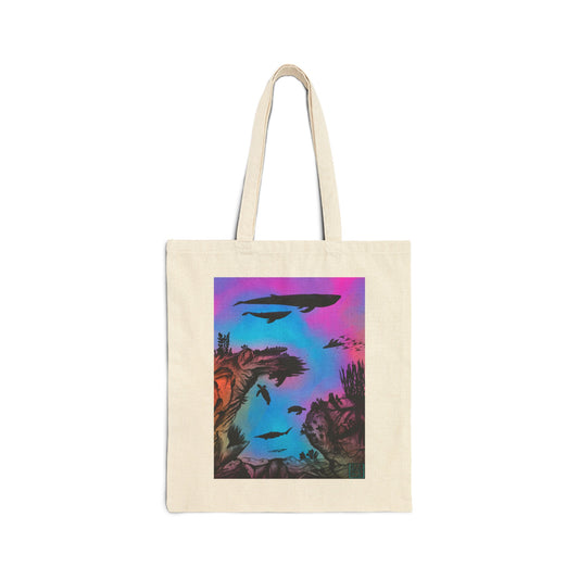 This is the Natural 15" x 16" Into the Abyss Canvas Tote by Lee Hansheng Studios. The illustration is underwater seascape with aquatic plants on a marbled background. There are two blue whales, 1 goblin shark, school of eagle rays, two sea turtles and a school of fish. On the bottom right corner is the studio logo printed in black outlined in blue. The colors are pink, purple, blue and red/orange. It is against a white background.