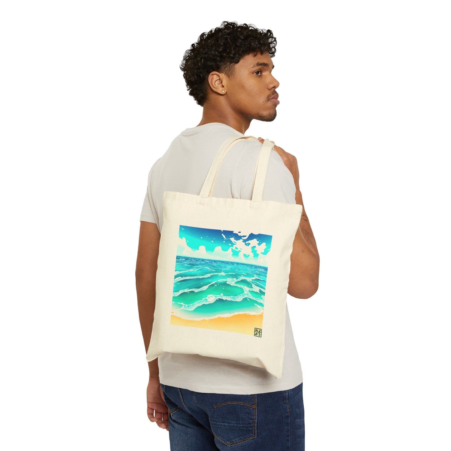 This is the Natural 15" x 16" Beach Life Canvas Tote by Lee Hansheng Studios. The illustration is squared,the foreground has sand and the studio logo on the right corner outlined in blue. The waves are crashing into the sand with fluffly clouds in the back. There are mixes of blue, light blue, white, orange and tan colors. A man looking to the right is holding the handles with the tote over his shoulder showing the front and wearing a white tee and dark jeans. 