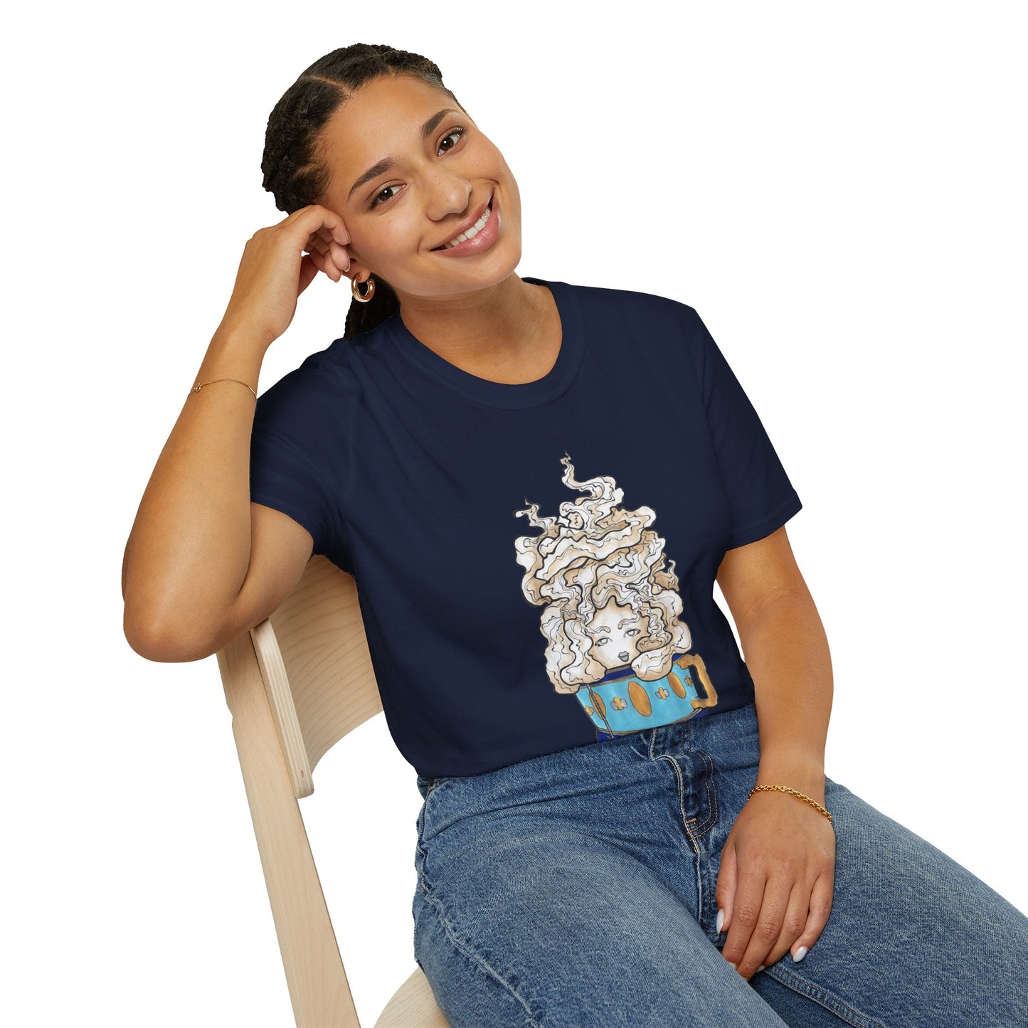 This is the Navy Earl Grey Softstyle T-Shirt by Chris Foster Design. It comes in sizes XS-5XL. The illustration is of a gold, light blue and dark blue teacup with a tan, yellow and white steam. The steam is swirly and goes up and outwards. In the middle is a lady's face. A smiling lady is sitting on a light wood chair with the backrest to the left, elbow on the back rest, dark jeans, looking to the front and wearing the t-shirt. 