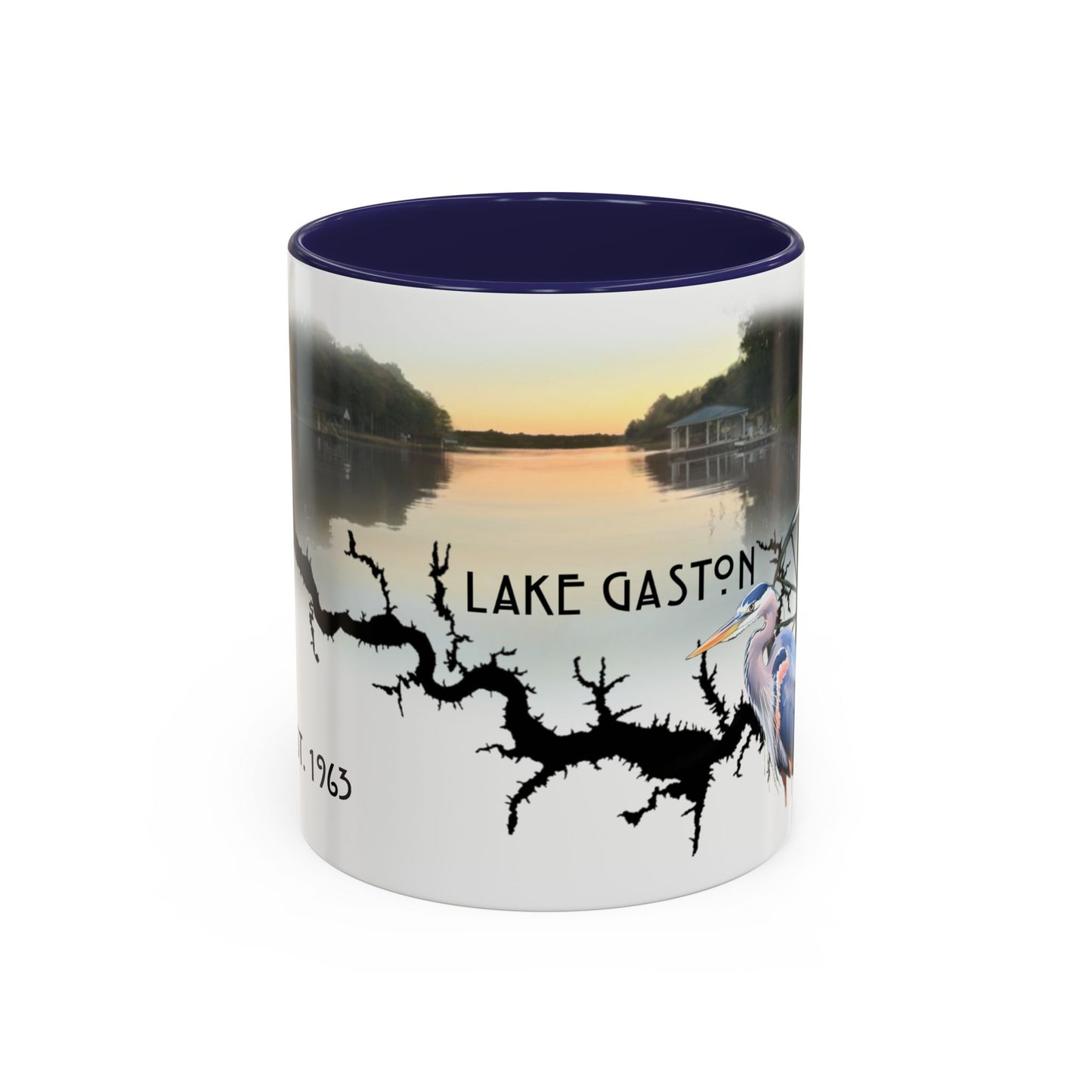 This is the 11oz Navy Lake Gaston Mug. It is an illustration by Lee Hansheng Studios. The picture is showing the front side of the mug. The inside of mug are color matched too. The mug is all white except for the illustration and handle. The illustration shows the lake on a horizon, the words "Lake Gaston", a black branch, and a blue heron on the right. The colors are orange, blue and green for the landscape. The mug is against a white background in the picture. 