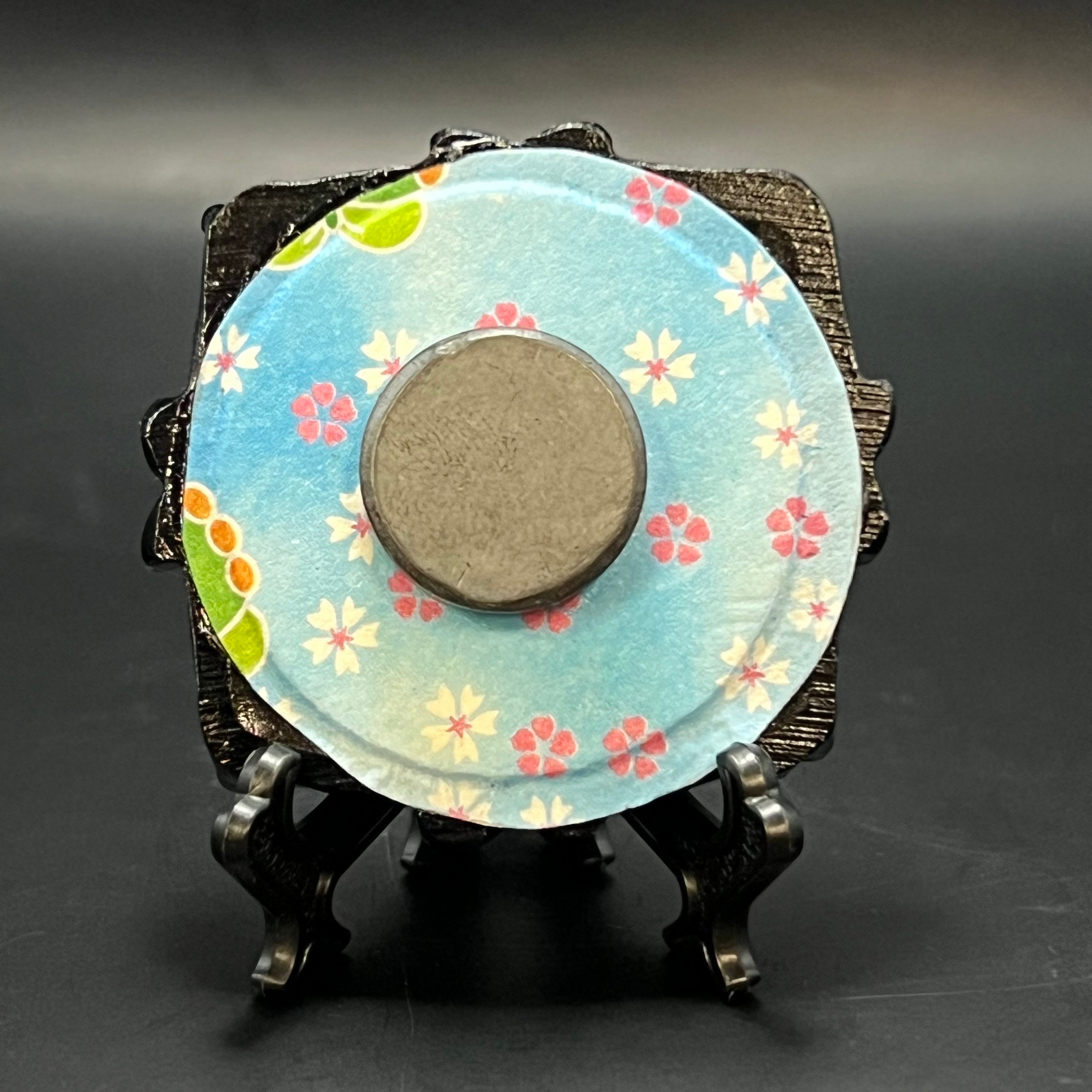 Close-up of the textured canvas surface highlighting the delicate plum blossom details and vibrant color accents in the