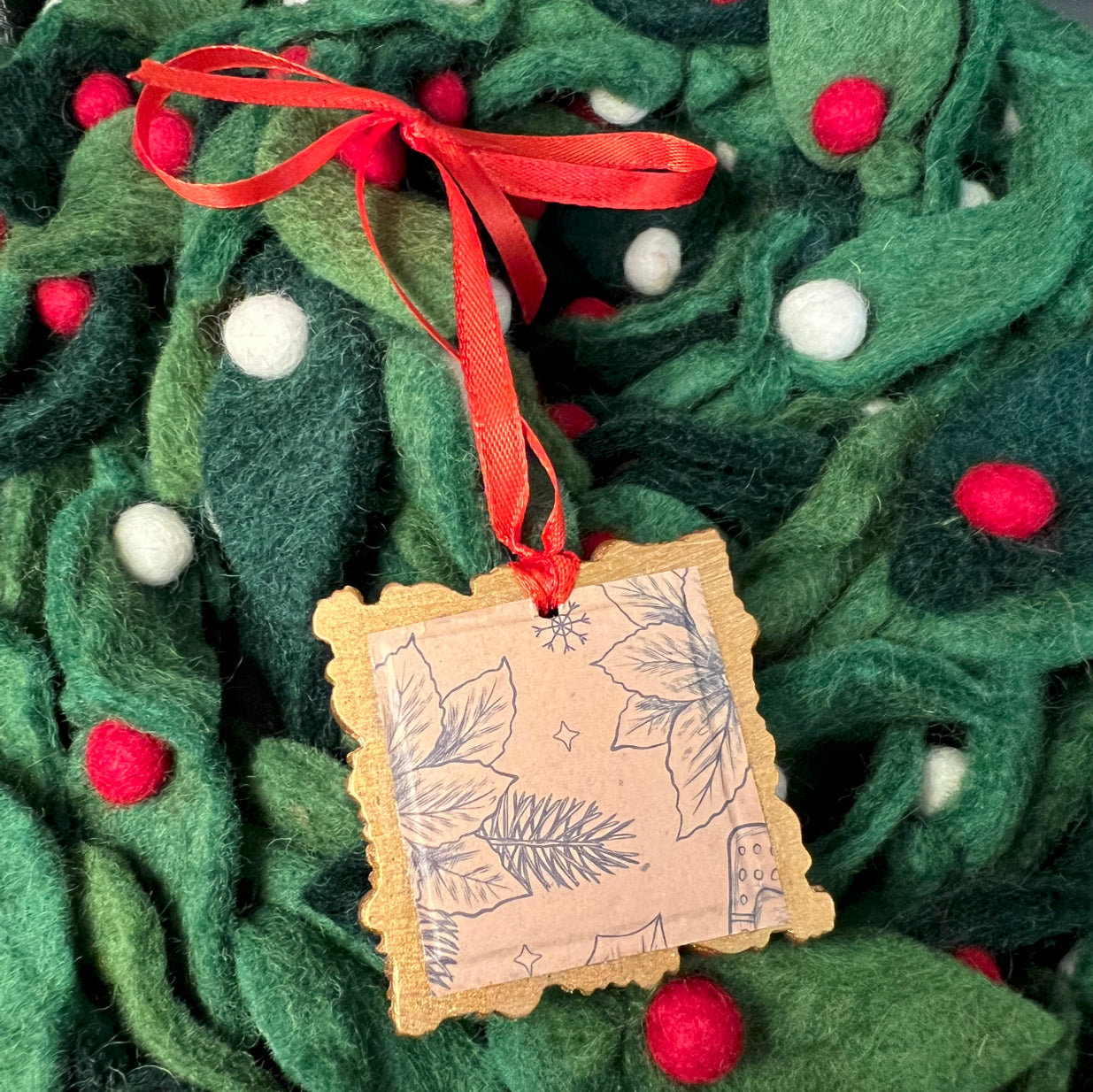 Close-up of the glittering red ribbon ornament's textured satin surface and intricate gold accents on the front