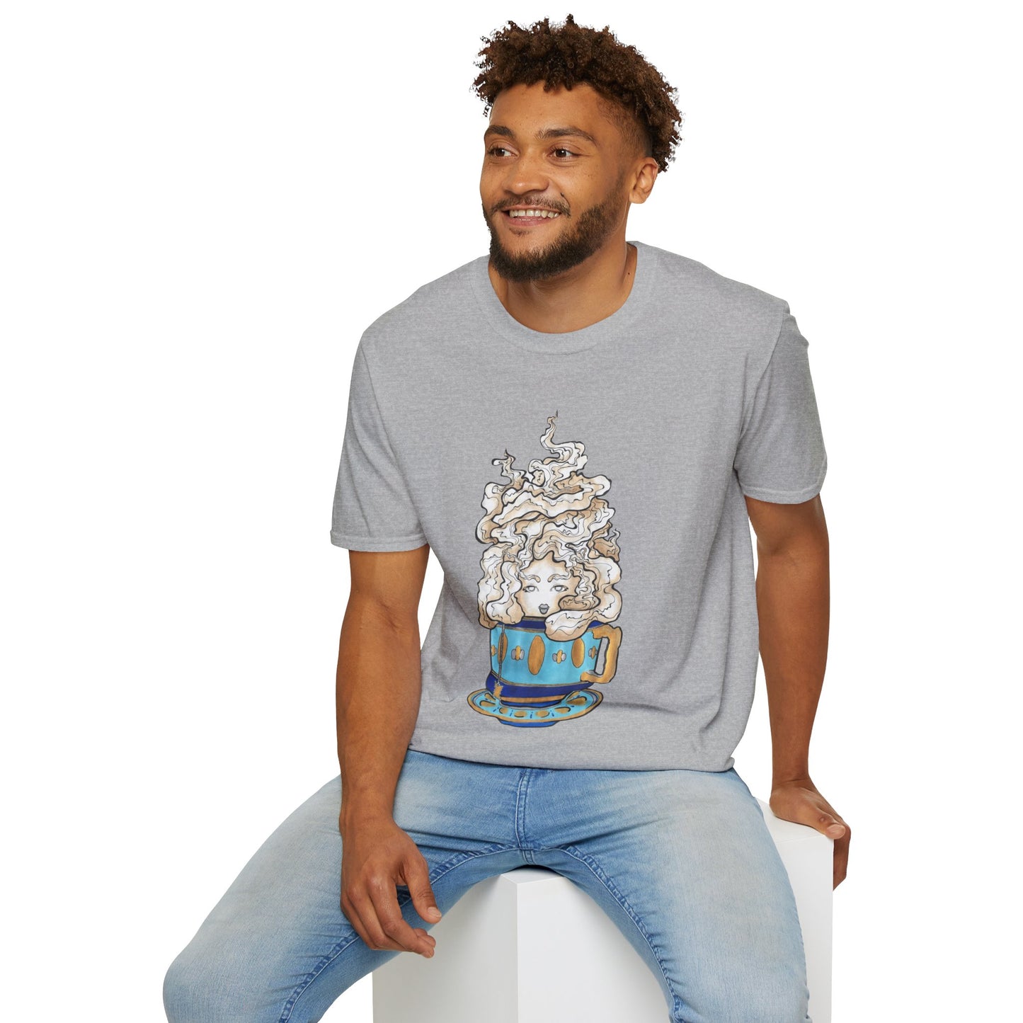 This is the Sport Grey Earl Grey Softstyle T-Shirt by Chris Foster Design. It comes in sizes XS-5XL. The illustration is of a gold, light blue and dark blue teacup with a tan, yellow and white steam. The steam is swirly and goes up and outwards. In the middle is a lady's face. A smiling man sitting on a white podium with one hand on the back edge, light jeans, looking to the left and wearing the t-shirt. 