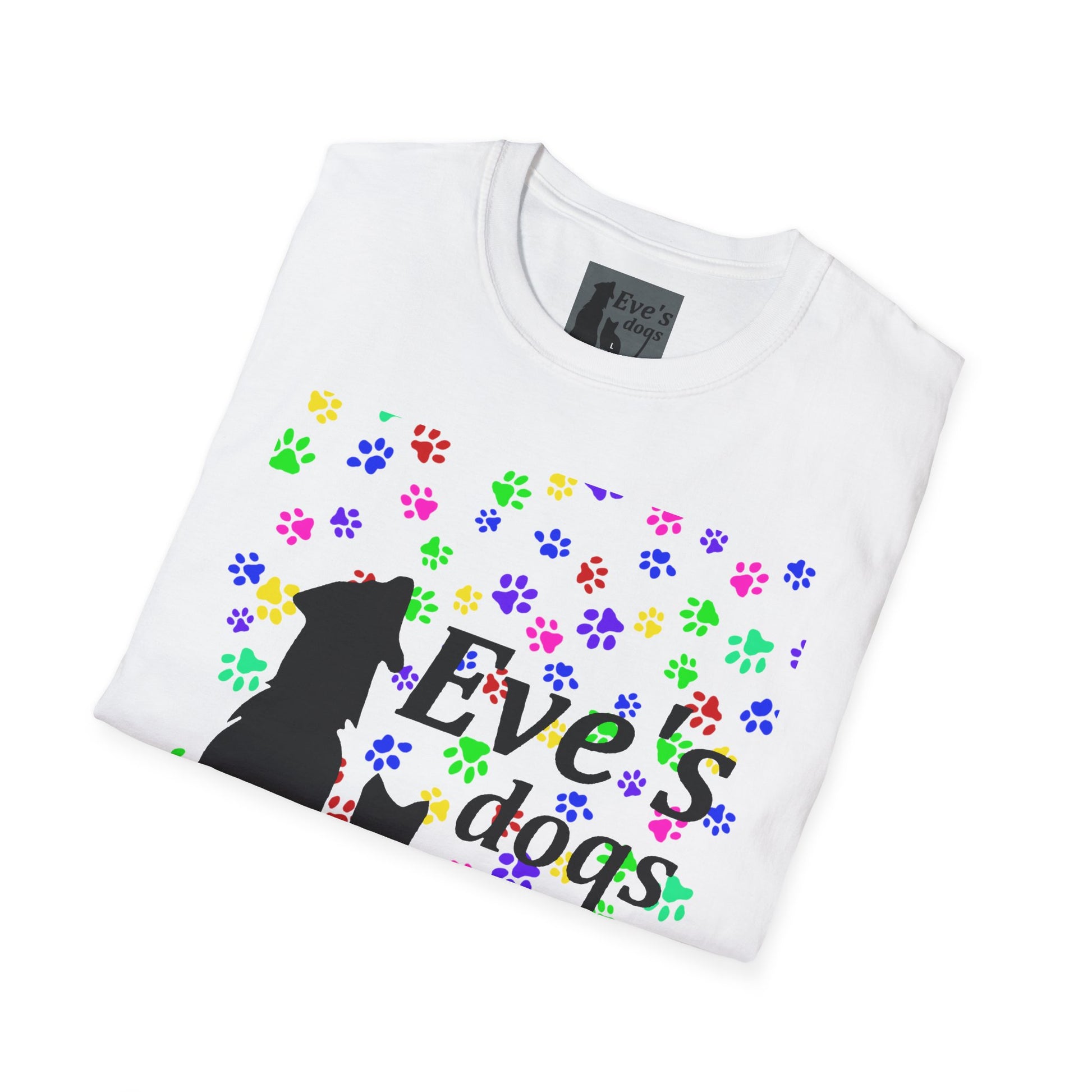 This is the White Adopt Eve's Dogs T-Shirt. It comes in XS - 5XL. The image is the shirt folded and showing the front. The size label is a grey and black tag with a dog and cat with the "Eve's dogs" writing. The front has pink, green, blue, purple, red paw prints in different sizes. Also, the dog and cat with "Eve's dogs" printed in black. It is against a white background.