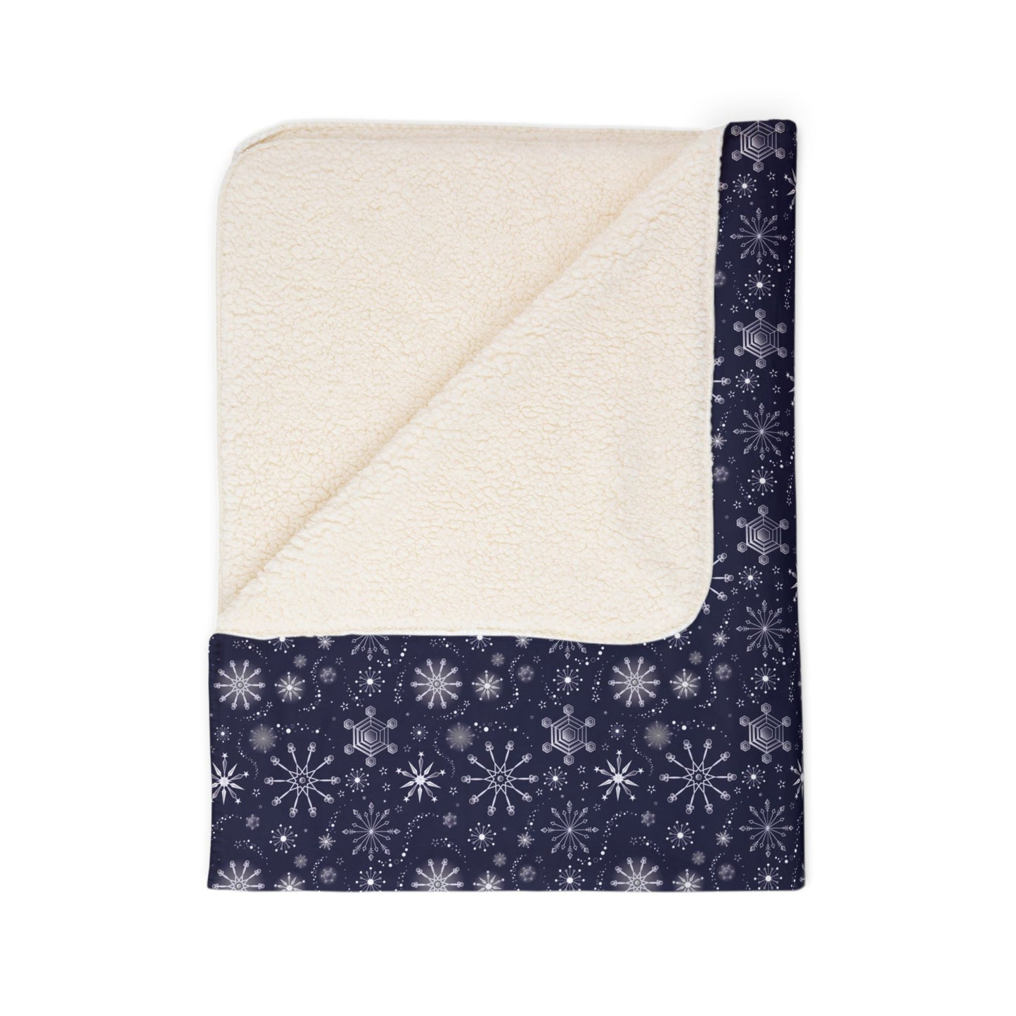 This is the beige 60" x 80" Winter Blizzard Sherpa Blanket. The blanket is folded. It is then revealed at the corner to show the inside sherpa and color. The background is white. The design are different types of snowflakes with different sizes of circles within each flake. The blanket is dark blue and the snowflakes and design are all white and spread throughout.