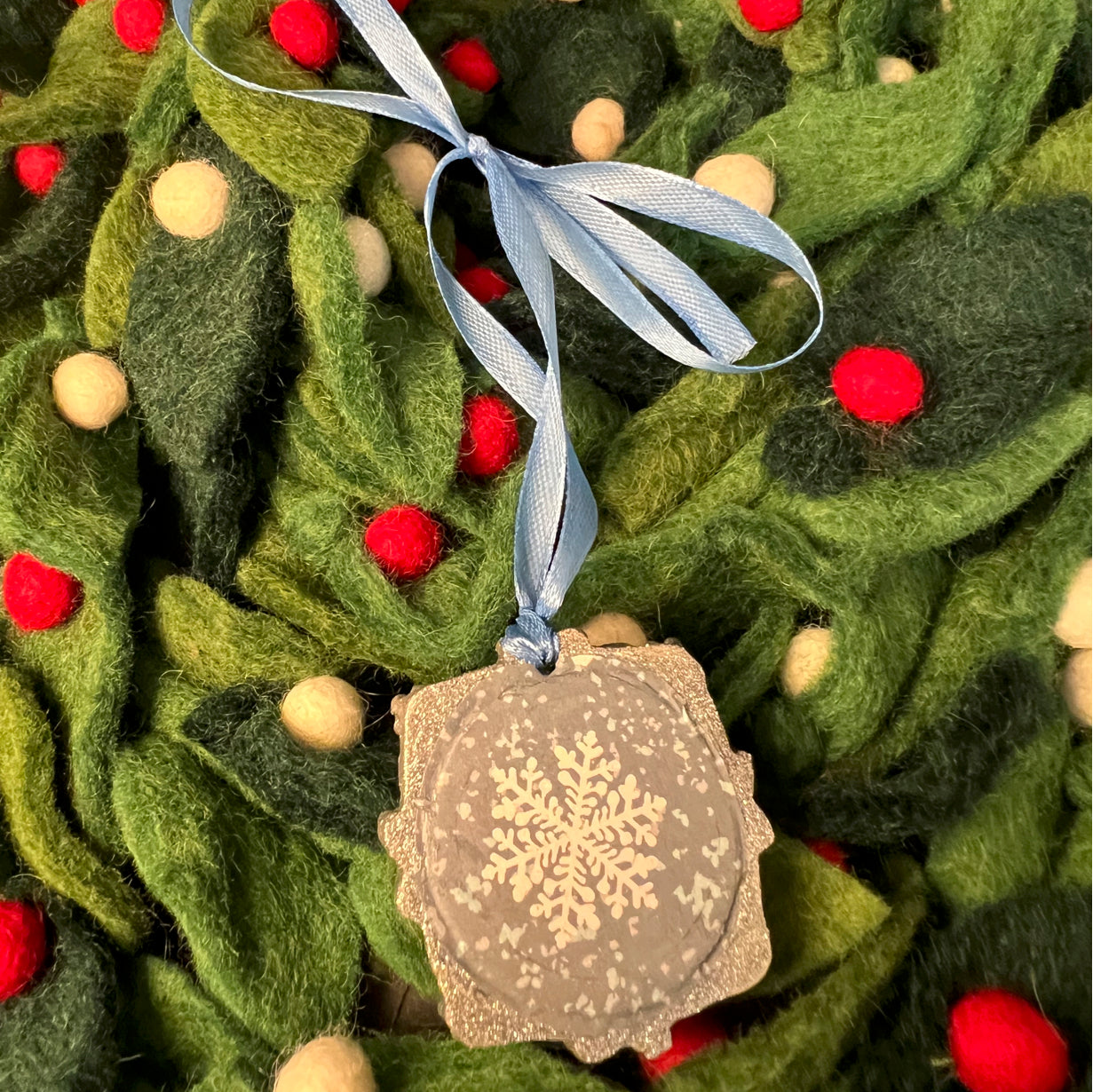 Close-up of the textured, glitter-coated snowflake details showing intricate cutout patterns and shimmering silver finish.